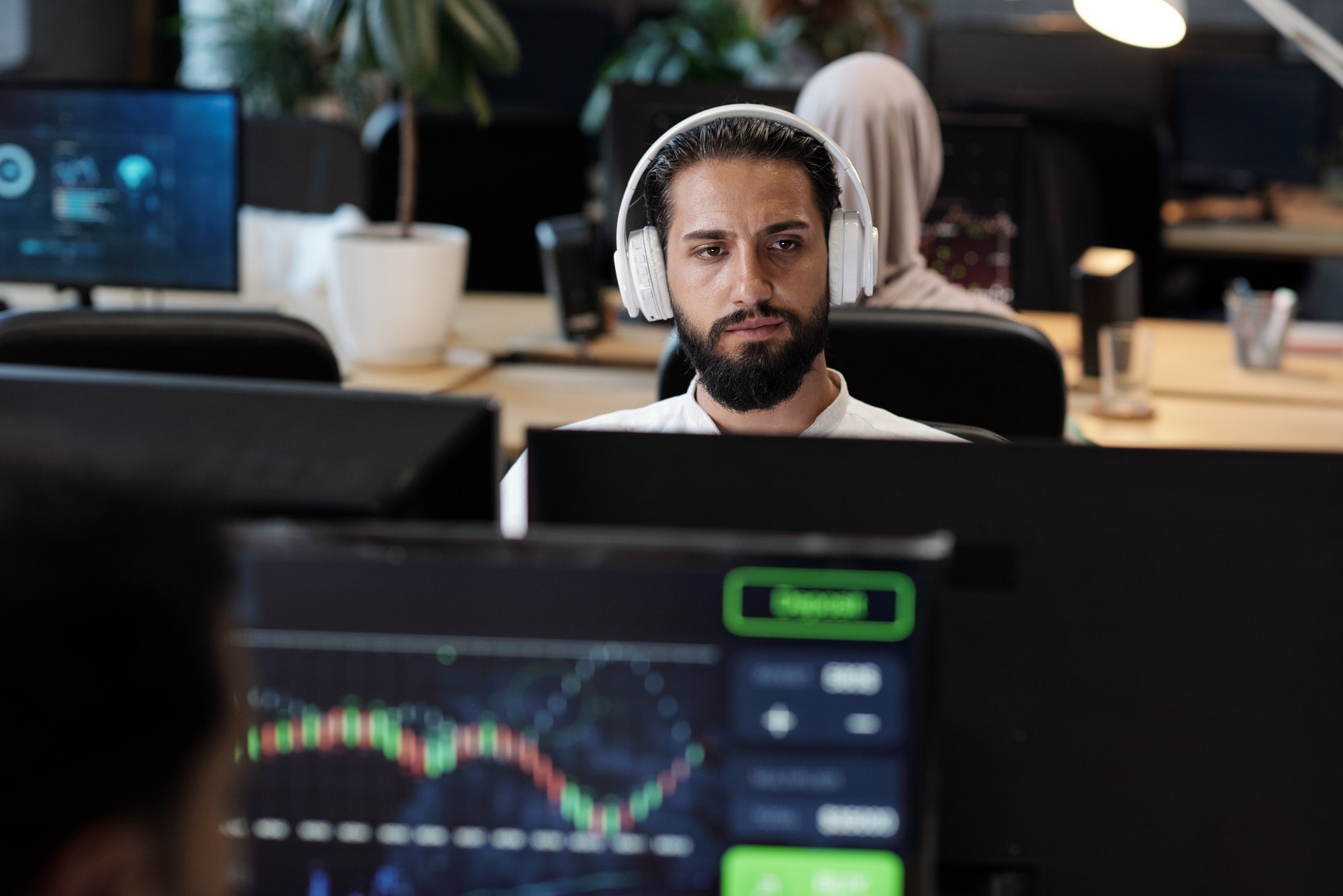 Bearded Arabic businessman in headphones looking at computer screen